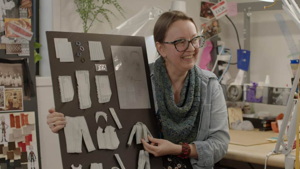 Costume design for ShadowMachine, Elsa, holding board with clothing components